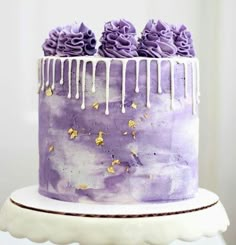 a purple cake with white icing and flowers on top