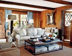 a living room with wood paneling and white couches in front of large windows