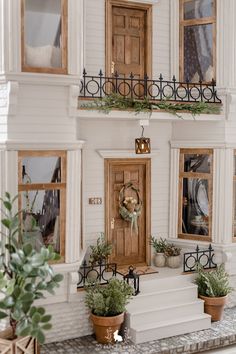 a white house with potted plants on the front steps