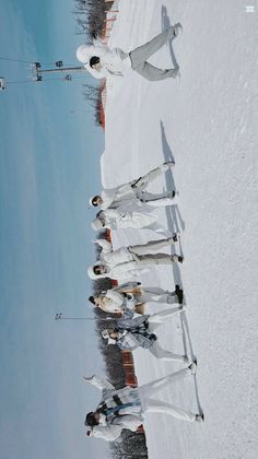 a group of people standing on top of a snow covered slope next to each other