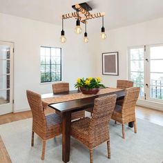 a dining room table with four chairs and a bowl of flowers on the centerpiece