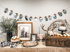 a dessert table with cupcakes, cookies and framed pictures