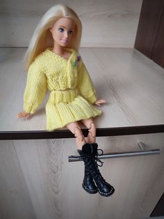 a doll sitting on top of a wooden shelf