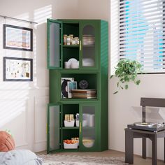 a green cabinet in the corner of a room next to a table with food on it