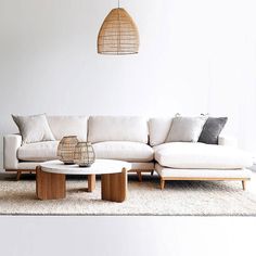 a white couch sitting on top of a rug next to a coffee table and lamp