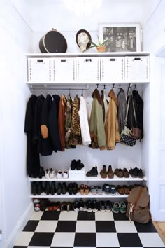 an organized closet with shoes, coats and handbags hanging on the wall next to it