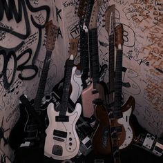 several guitars are lined up against a wall with graffiti on the walls and flooring