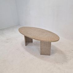 an oval stone table sitting on top of a white carpeted floor next to a wall