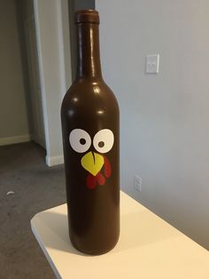 a brown bottle with a face drawn on it sitting on a white table in front of a door