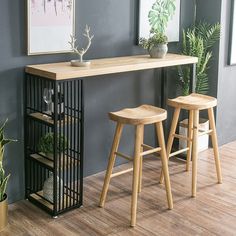 two wooden stools sitting next to a table with plants on it and a potted plant in the corner