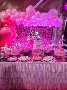 a table topped with lots of pink and white desserts next to balloon filled walls