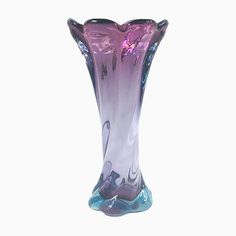 a purple and blue glass vase sitting on top of a white table next to a wall