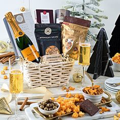 an assortment of snacks and wine on a table next to a christmas tree with decorations