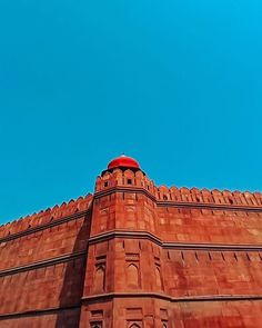 the top of a tall brick building with a red dome on it's roof