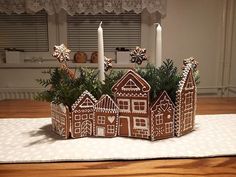 a gingerbread house is sitting on top of a placemat with candles in the background