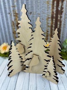 three wooden trees on a table with flowers in the background