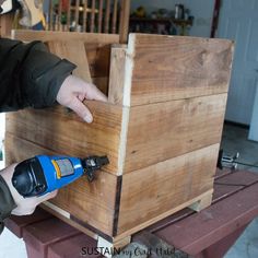 a person using a drill to attach the top of a wooden box