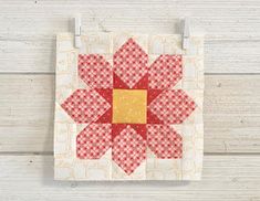 a red and white quilt with a flower on the front, hanging from a hook