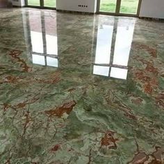 an empty room with large windows and green marble flooring