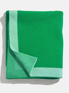 a green and white blanket folded on top of each other with a light blue stripe down the middle