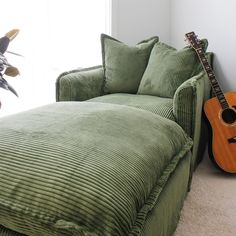 a guitar sitting on top of a couch next to a plant in a living room