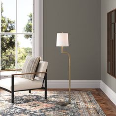 a living room with a chair, lamp and rug on the hardwood floor next to a large window