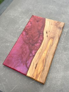 a piece of wood sitting on top of a cement floor next to a red object