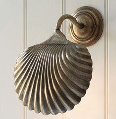 a brass scallop mounted to the side of a white door with a light on it