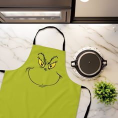 an apron with the grin face drawn on it next to a potted plant and pan