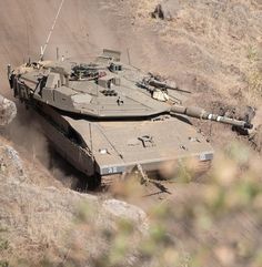 an army tank driving down a dirt road