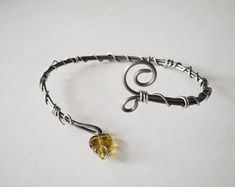 a silver bracelet with a yellow glass bead on the end and a wire wrapped around it