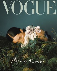 a woman laying on top of a lush green field next to a magazine cover with a butterfly