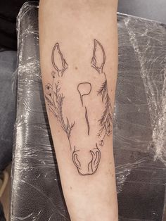 a tattoo on the leg of a person with a horse's head and flowers