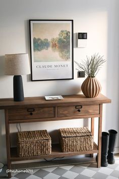 a wooden table with two baskets underneath it and a painting on the wall behind it