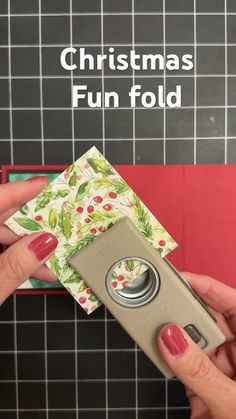 a person holding an electronic device in front of a tiled wall with the words christmas fun fold on it