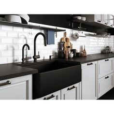 a kitchen with black counter tops and white cupboards on the wall above the sink