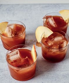 three glasses filled with ice and apples on top of a marble countertop next to an apple slice