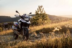 a motorcycle parked on the side of a dirt road next to some grass and trees