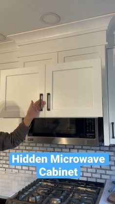 a woman is taking a picture of the microwave above her kitchen countertop and cabinets