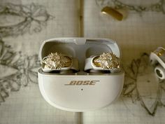 two pairs of gold colored earrings sitting in an earbud case