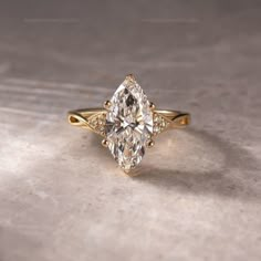 a yellow gold engagement ring with a pear shaped diamond in the center and side stones