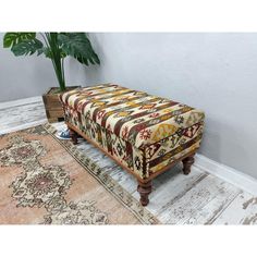 a bench sitting on top of a wooden floor next to a rug and potted plant