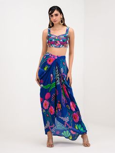 A three-piece Marine Blue Printed Dhoti Skirt Set Paired With Bralette and Cape from the Juhi Bengani collection – Festive 2023. This gorgeous marine blue printed dhoti skirt is paired with a heavy embroidered bralette blouse. The bright and vibrant prints with bird and floral work, heavy embroidery of beads, and thread sequence work enhance this pure crepe dhoti skirt set. This outfit is completed with a marine blue printed cape with embroidered lace border. Dhoti Lehenga, Off Shoulder Lehenga, Dhoti Skirt, Skirt Cape, Hand Embroidered Blouse, Cape Set, Western Dresses For Women, Raw Silk Lehenga, Green Lehenga