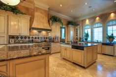 a large kitchen with marble counter tops and beige cabinets