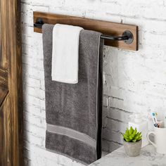 a towel rack with two towels hanging from it's sides next to a white brick wall