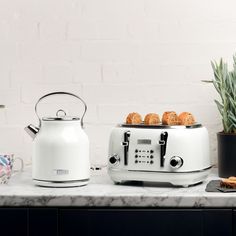 a white toaster sitting on top of a counter next to a potted plant