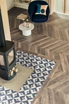 a living room with wood flooring and a blue chair in the corner next to a fireplace