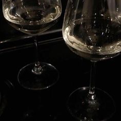 two wine glasses sitting on top of a counter in front of a black oven door