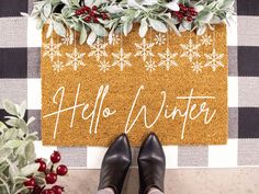 a person standing in front of a door mat that says hello winter