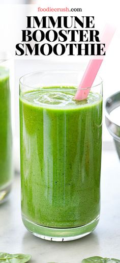 a green smoothie in a glass with a pink straw on the top and another one behind it